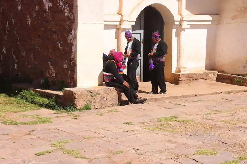 Moradores com trajes tradicionais junto a um arco de pedra na Ilha Taquile